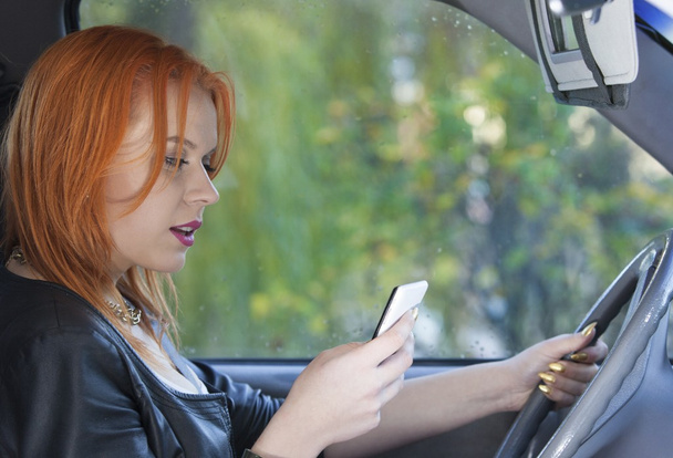 Woman driver sending text reading message on phone while driving - Fotó, kép