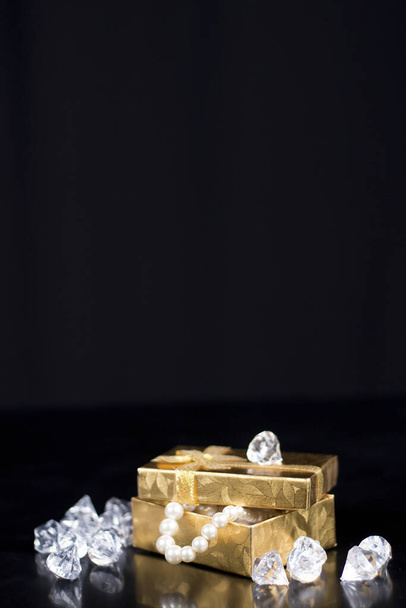 Siyah parlak arkaplanda parlak inciler olan altın mücevher kutusu. - Fotoğraf, Görsel
