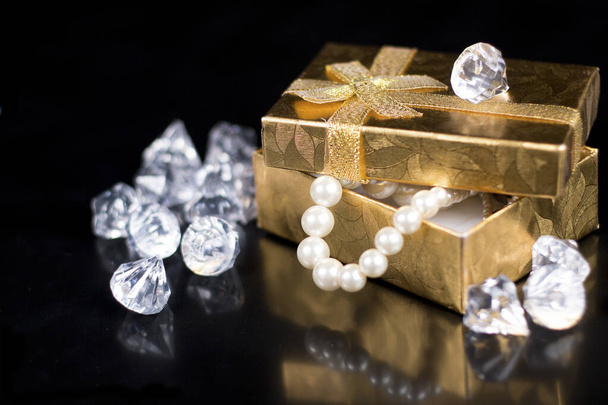 Arany ékszer doboz fényes gyöngyökkel, fekete fényes háttér - Fotó, kép