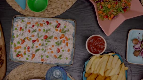 dinner table with fries and ketchup, mayo sauces, delicious grilled meat, russian salad, delicious meatballs dressed with onions, seasonings and parsley close up - Footage, Video