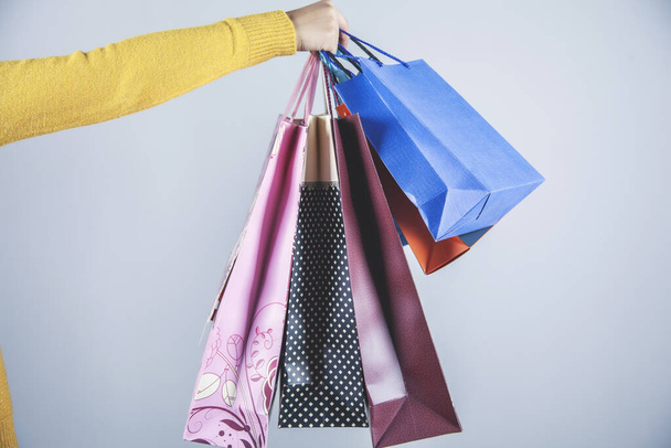 woman hand holding shopping bags on gray background - Foto, afbeelding