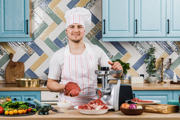 生肉だ。ミンチ肉の調製工程は、ミートグラインダーで行います。男性シェフは台所で肉の粉砕機を使用します。 - 写真・画像