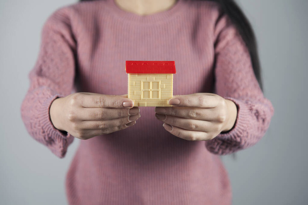 woman hand house model on gray wall background - Foto, immagini