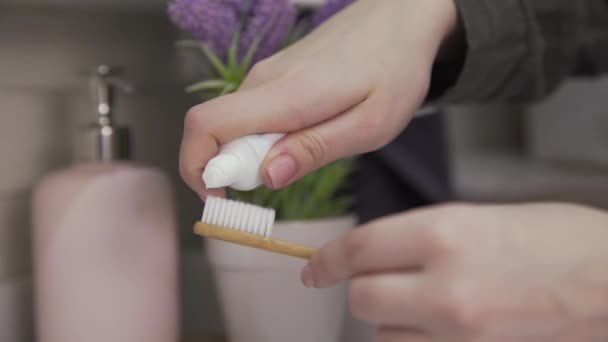Zblízka žena klade zubní pastu na kartáček - Záběry, video