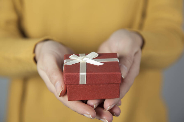mujer mano sosteniendo caja de regalo sobre fondo gris
 - Foto, Imagen