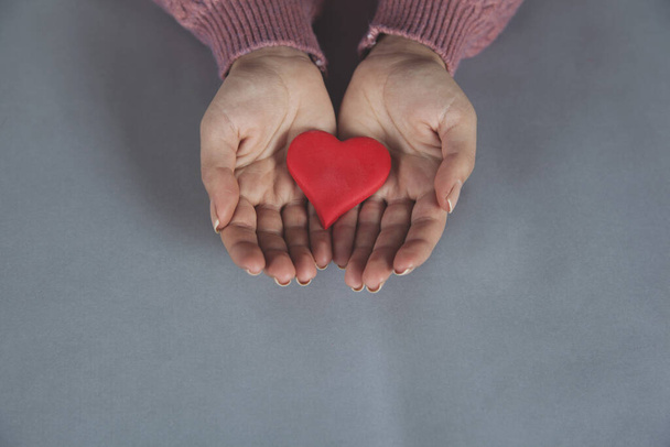 Heart in girl's hands against gray background - Фото, изображение