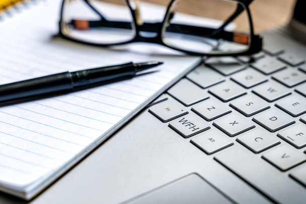 WFH - Makro pohled na práci z domovského tlačítka na klávesnici notebooku s poznámkovým blokem a perem - Fotografie, Obrázek