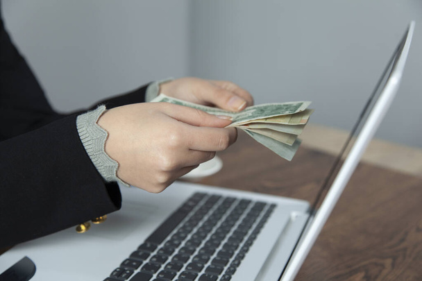 woman hand money with computer screen on desk - Zdjęcie, obraz