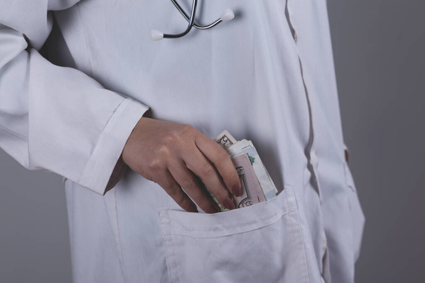 Female doctor hand money on the pocket background - Фото, зображення