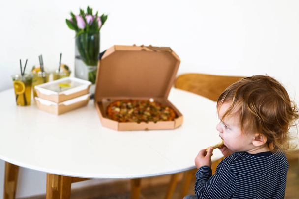 bambino seduto a tavola a mangiare pizza
 - Foto, immagini