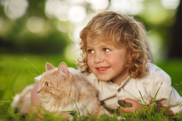 Pequeño chico rizado con un gato pelirrojo
 - Foto, Imagen