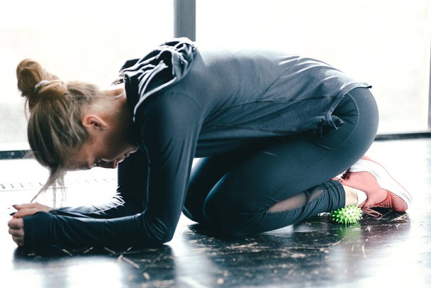 Close-up female in black leggings. Exercising the muscles with a green myofascial ball. - Foto, immagini