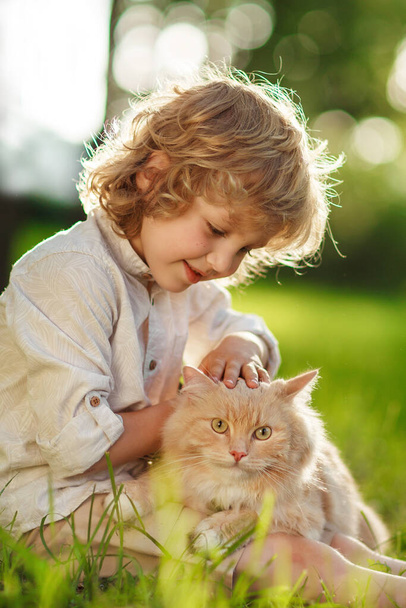 Kleine krullende jongen met een roodharige kat - Foto, afbeelding