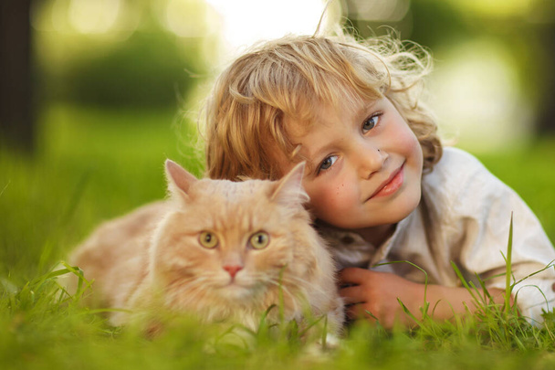 Pequeño chico rizado con un gato pelirrojo
 - Foto, Imagen