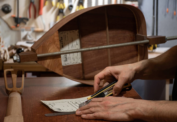 une scène rapprochée des mains de luthier découpant des titres faits à la main pour instruments de musique en bois
 - Photo, image
