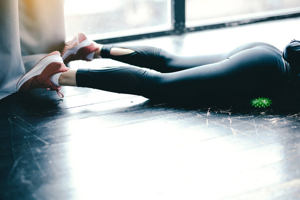 Close-up female in black leggings. Exercising the femoral muscles with a green myofascial ball. - Foto, imagen