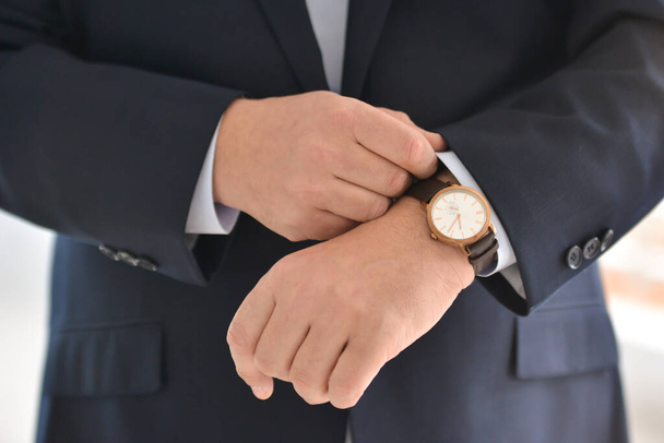 Correct wristwatches on hand close-up, dressing, man's style, stylish man. Elegant young handsome man. Men's jacket, hand cover the button. Business style. - Фото, зображення