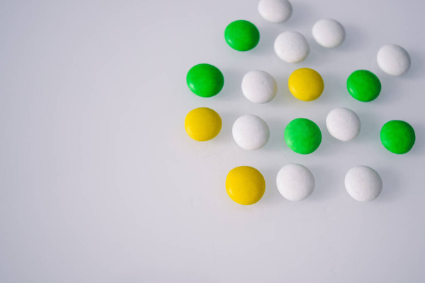 tablets or candies, white and colored on a white table  - 写真・画像