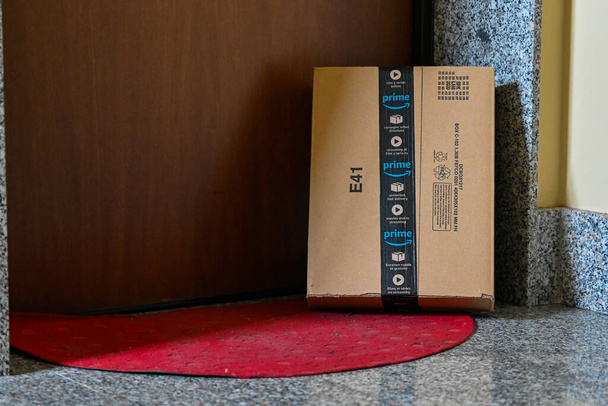 Turin, Piedmont, Italy. April 2020. Quarantine and social distance. The coronavirus causes amazon parcel deliveries to take place with the parcel left next to the customer's door, on the red carpet. - Photo, image