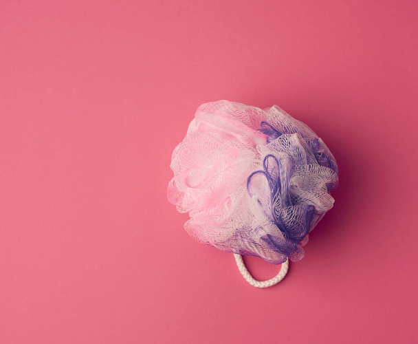 round synthetic washcloth on a pink background, top view - Fotografie, Obrázek