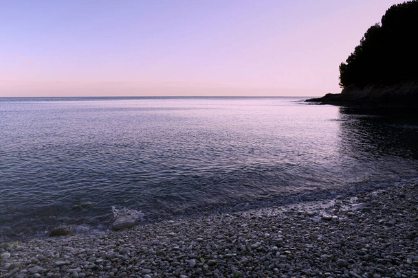 Υπέροχο σούρουπο σε όμορφη γαλάζια λιμνοθάλασσα με βότσαλο παραλία. Εκπληκτικό φόντο της φύσης - Φωτογραφία, εικόνα
