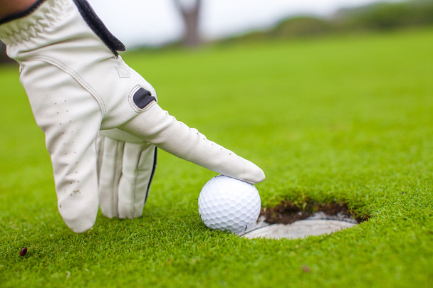 Golf player man pushing golfball into the hole - 写真・画像