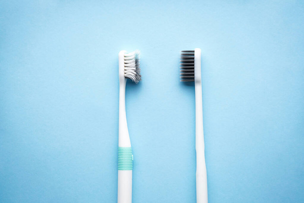 Concept de soins dentaires et de santé. Brosses à dents neuves et anciennes sur fond bleu, plan rapproché, plan plat
. - Photo, image
