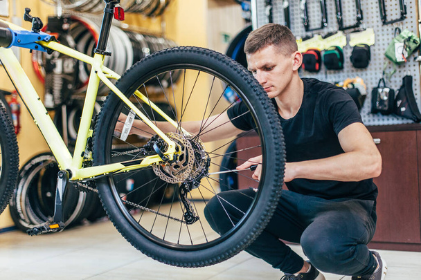 Guy is repairing a bicycle in a bicycle workshop - Zdjęcie, obraz