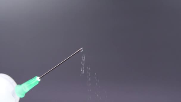 A syringe needle releases a drop of clear liquid - Video