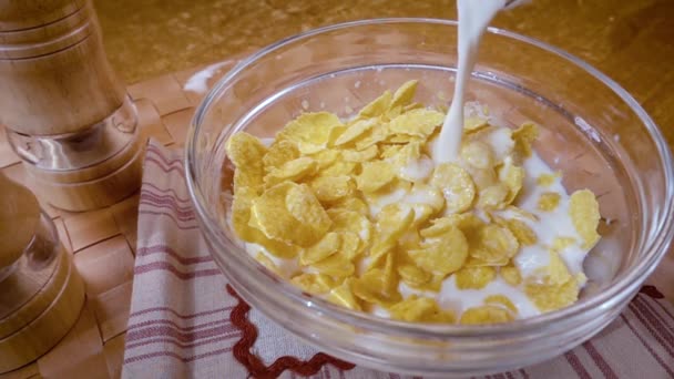 Crispy yellow corn flakes into the bowl for the morning a delicious Breakfast with milk. Slow motion with rotation tracking shot. - Video