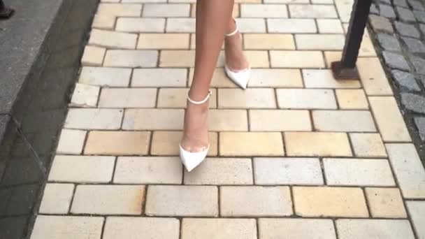 Blondine in einem pfirsichfarbenen Kleid und Schuhen geht die Straße hinunter - Filmmaterial, Video