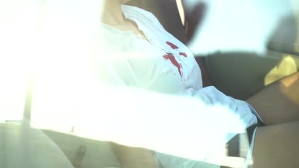 Μαύρο κορίτσι με αφρο χτένισμα με αίμα στο πρόσωπο και το πουκάμισό της ξυπνά μετά από ένα ατύχημα σε ένα κόκκινο αυτοκίνητο - Πλάνα, βίντεο