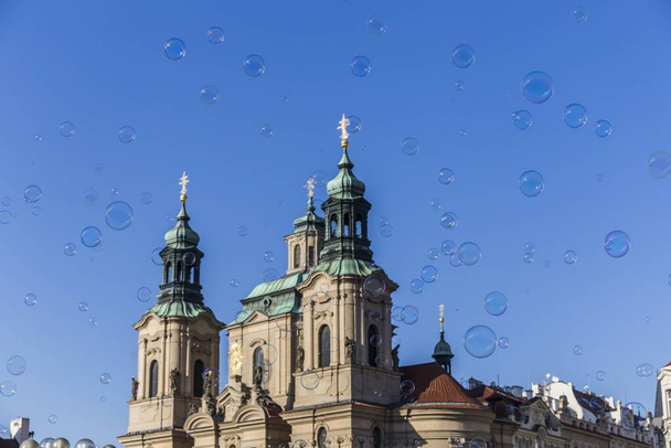 Hundreds of bubbles fly in the sky around a historic Prague building with pointy greenish domes and ornate faade  - Photo, image