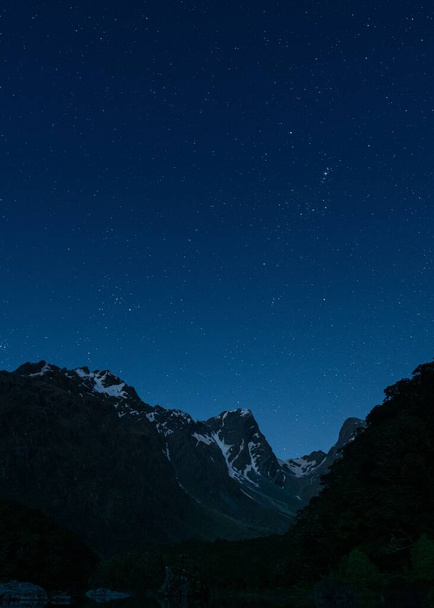 A függőleges lövés a hegyek alatt sötét kék ég tele csillagokkal - nagy a háttérben - Fotó, kép