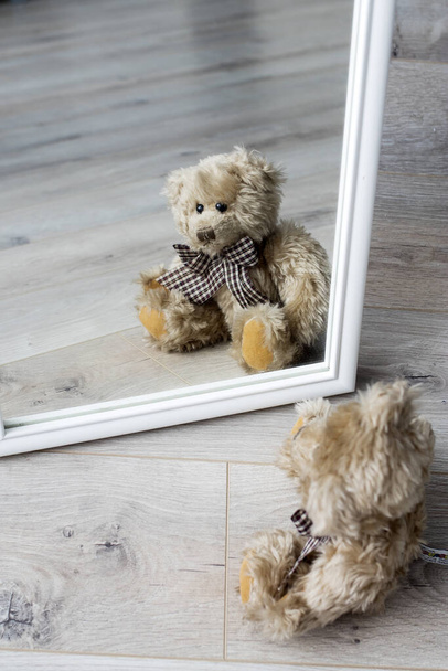teddy bear looks at his reflection in the mirror. Loneliness. The concept of self-isolation. Stay home. - Photo, Image