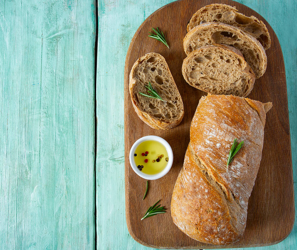 ciabatta bread and olive oil on wooden surface - Фото, зображення