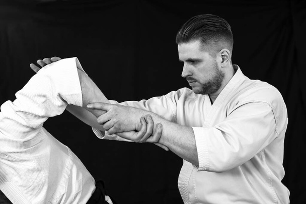Nahaufnahme eines jungen Mannes, der eine schmerzhafte Handtechnik aus der Aikido-Technik anwendet - Foto, Bild
