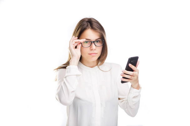 Portrait of caucasian young business woman uses smartphone on white background. Isolate. woman in office clothes looks at the phone, holds mobile phone in her hand. Theme Business and Technology. - Fotografie, Obrázek