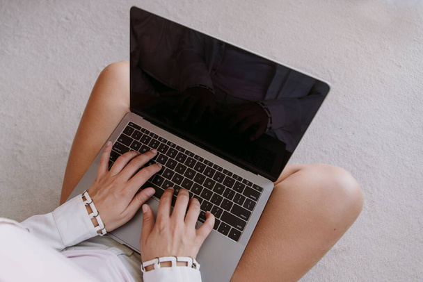 Top view és közelkép a fehér lány egy szürke számítógép ül a fehér és puha szőnyeg padlóján a hálószoba. Új információk és jogok. - Fotó, kép