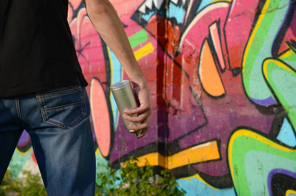 Joven artista de graffiti con mochila y máscara de gas en el cuello pinta coloridos graffiti en tonos rosados en la pared de ladrillo. Arte urbano y proceso de pintura contemporánea. Entretenimiento en la subcultura juvenil
 - Foto, Imagen