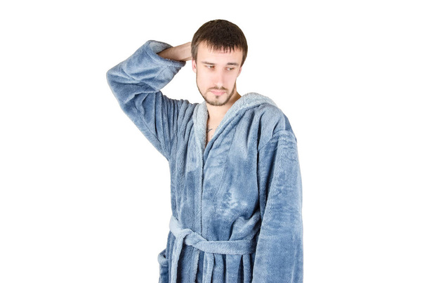 Portrait of young caucasian bearded man in blue bathrobe shows clueless emotion isolated on white background. Guilty facial expression concept - Foto, Bild