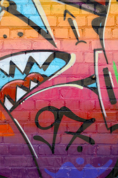 Abstract colorful fragment of graffiti paintings on old brick wall. Street art composition with parts of unwritten letters and multicolored stains. Subcultural background texture in red colors - Photo, Image