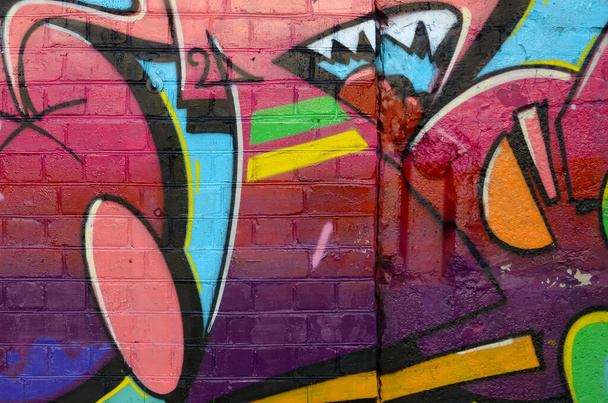 Abstrakcyjny kolorowy fragment malowideł graffiti na starej ceglanej ścianie. Uliczna kompozycja sztuki z częściami dzikich liter i wielokolorowymi plamami. Subkulturowe tło tekstury w ciepłych kolorach - Zdjęcie, obraz
