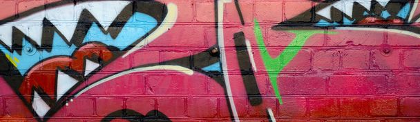 Αφηρημένο πολύχρωμο θραύσμα γκράφιτι πίνακες σε παλιά τοίχο από τούβλα. Σύνθεση δρόμου με μέρη από άγρια γράμματα και πολύχρωμους λεκέδες. Υφή υποπολιτιστικού φόντου σε ζεστά χρώματα - Φωτογραφία, εικόνα