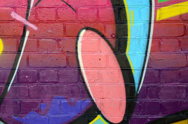 Abstract kleurrijk fragment van graffiti schilderijen op oude bakstenen muur. Street art compositie met delen van wilde letters en veelkleurige vlekken. Subculturele achtergrond textuur in warme kleuren - Foto, afbeelding