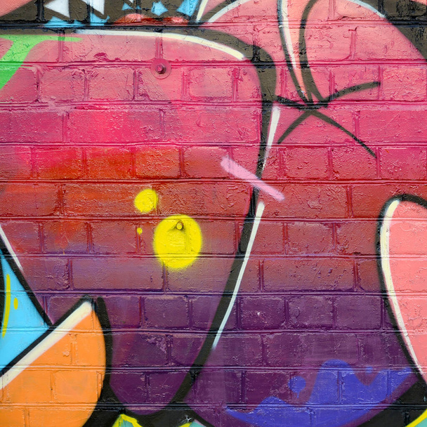 Абстрактний барвистий фрагмент графіті на старій цегляній стіні. Вулична композиція з частинами неписаних літер та різнокольоровими плямами. Субкультурна текстура тла в червоних кольорах
 - Фото, зображення