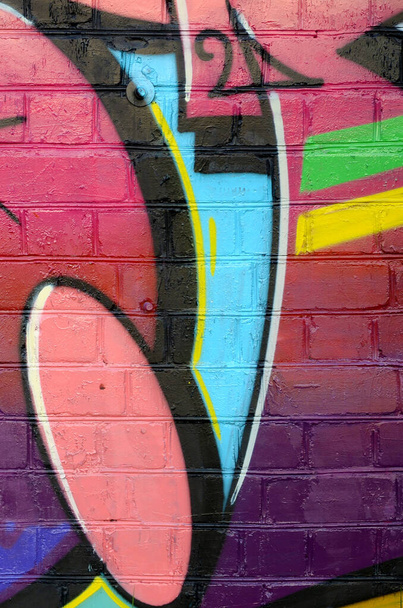 Abstract colorful fragment of graffiti paintings on old brick wall. Street art composition with parts of unwritten letters and multicolored stains. Subcultural background texture in red colors - Photo, Image