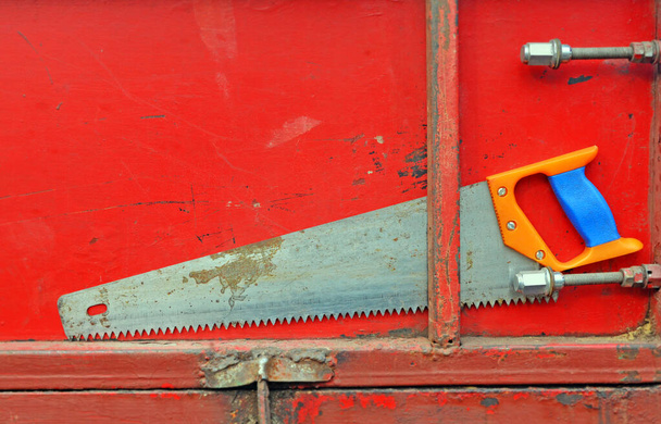 Vieja sierra de mano se adjunta a la puerta trasera del camión o remolque. Lado del cuerpo y dientes de herramienta en aserrín
. - Foto, imagen