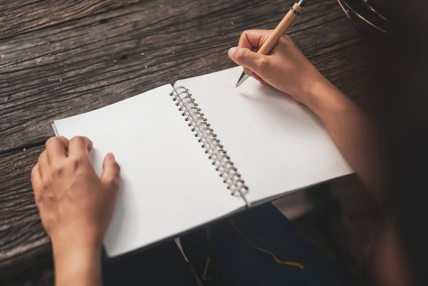 Mujer mano escribiendo en un pequeño cuaderno blanco para tomar una nota para no olvidar o hacer un plan de lista para el futuro. - Foto, imagen