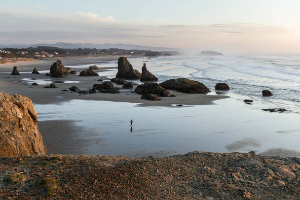 Spokojne popołudnie w Bandon Oregon z odpływami odsłaniającymi piaszczystą plażę z dużymi skałami dodającymi dramatu krajobrazowi południowego wybrzeża Oregonu - Zdjęcie, obraz
